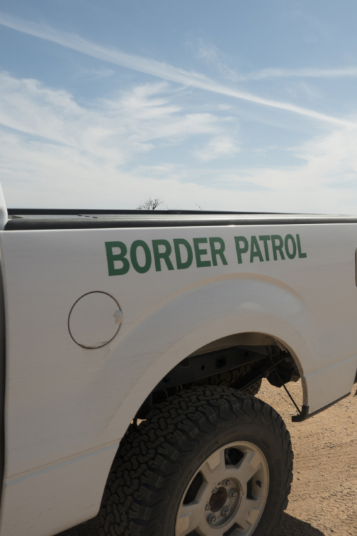 Image of the back end of a border patrol pickup truck and desert landscape