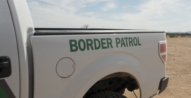 Image of the back end of a border patrol pickup truck and desert landscape