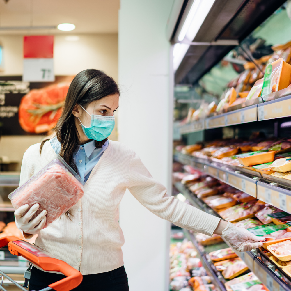Woman wearing a mask shopping for meat at a grocery store