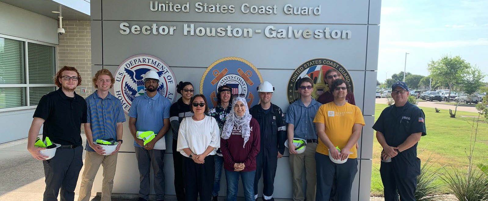 Students in a group posing for a picture in front of a U.S. DHS and Coast Guard sign with a member of the Coast Guard in Galveston
