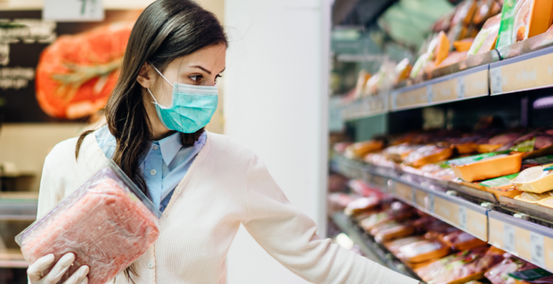 Woman wearing a mask shopping for meat at a grocery store